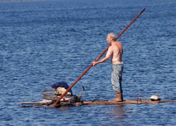 Путешественник переплыл спокойное озеро на яхте. Человек плывет на бревне. Люди на плату. Человек на плоту. Мужик на лодке.